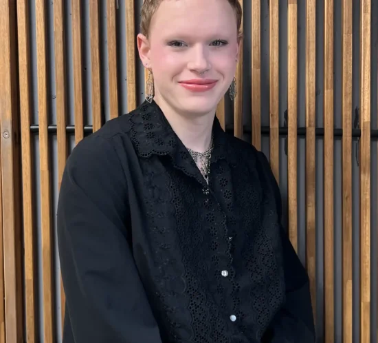 James standing in front of a wooden background.