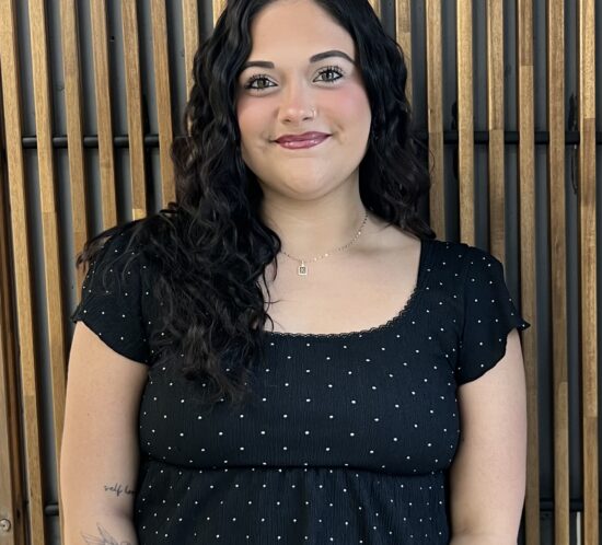 Kayla standing in front of a wooden background.
