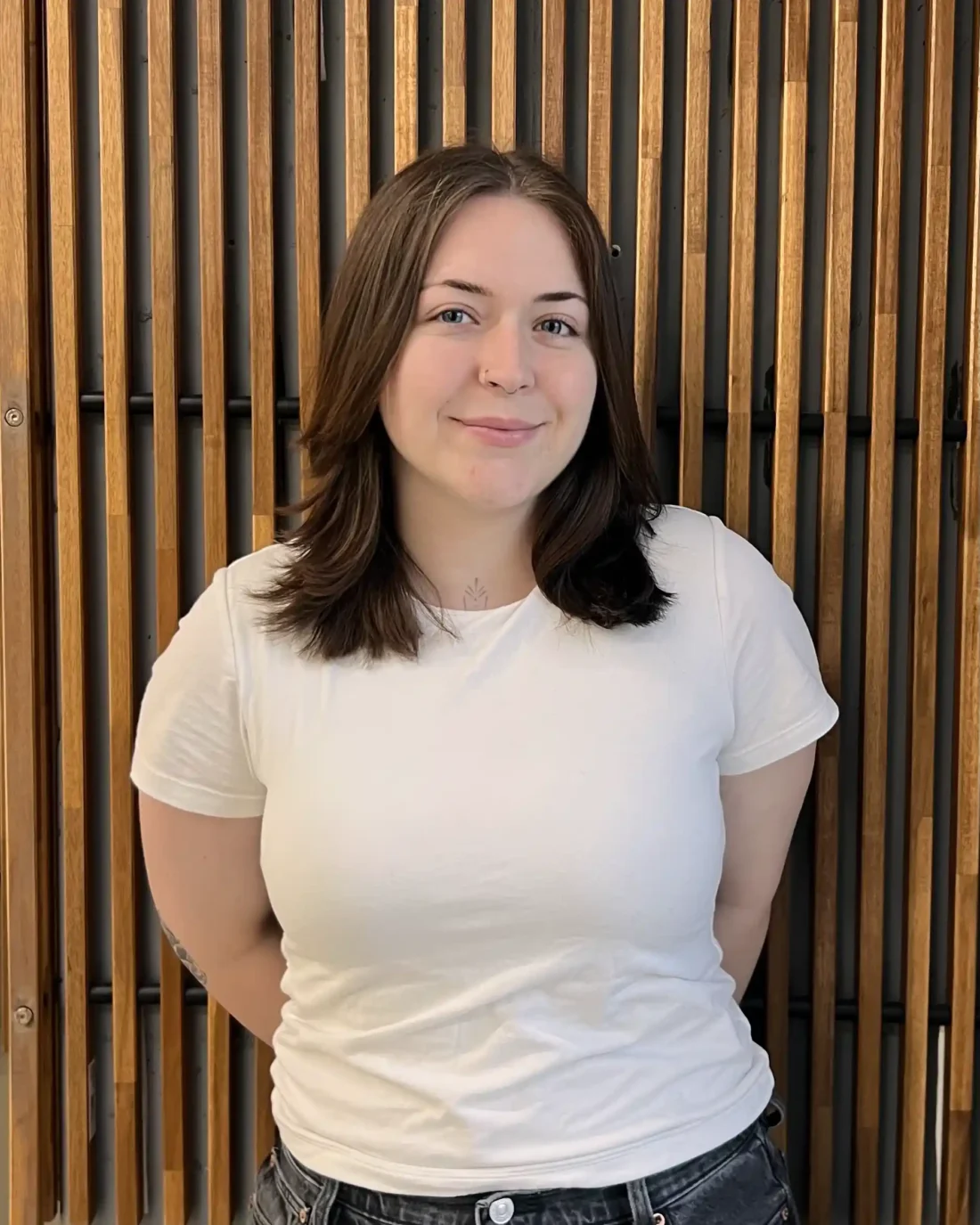 Madie standing in front of a wooden background.