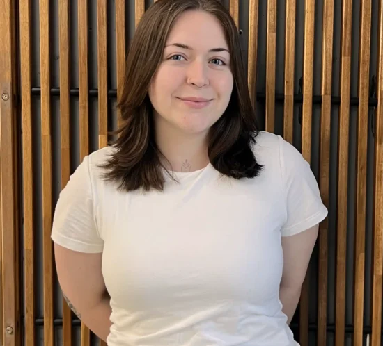 Madie standing in front of a wooden background.